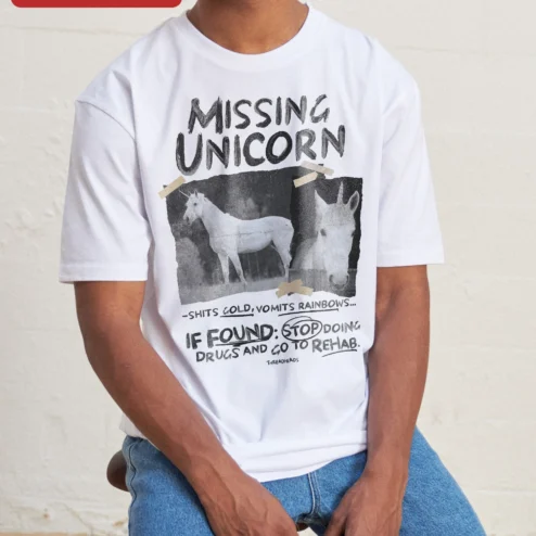 Missing Unicorn Shits Gold Vomits Rainbows Funny Sarcastic Graphic Tee on a hanger, ready to ship from Chicago, Illinois