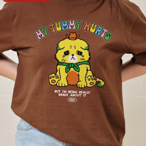My Tummy Hurts But I'm Being Really Brave About It Funny Dog Graphic Tee on a hanger, ready to ship from Chicago, Illinois