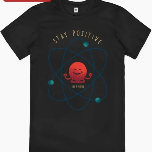 Stay Positive Like A Proton Tee Funny Science Joke Shirt for Physics Teachers and STEM Students on a hanger, ready to ship from Chicago, Illinois