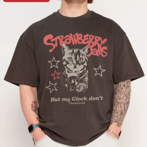 Strawberry Jams But My Glock Don't Funny Cat Graphic Tee on a hanger, ready to ship from Chicago, Illinois