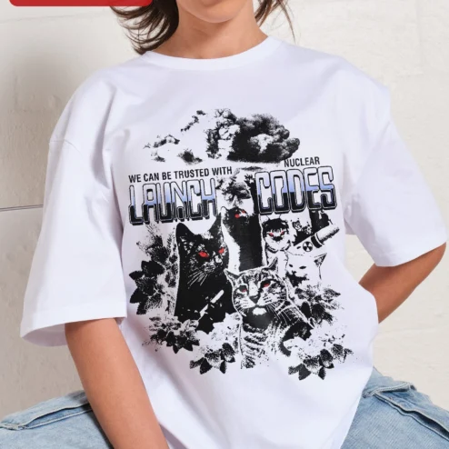 We Can Be Trusted With Nuclear Launch Codes Sarcastic Cat Graphic Tee on a hanger, ready to ship from Chicago, Illinois